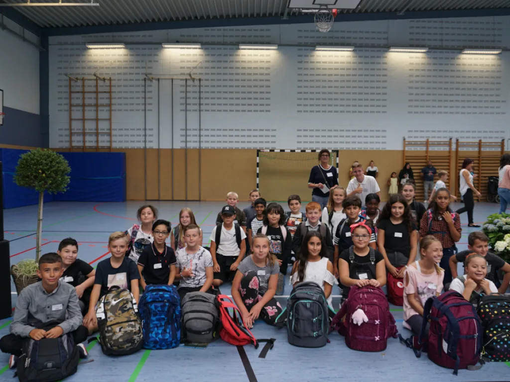 Neue fünfte Klasse sitzt in der Sporthalle.